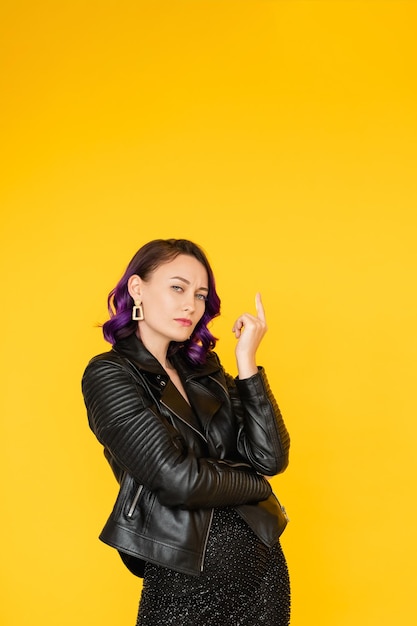 Advertising product Confident woman Important information Sale promotion Serious lady in stylish leather jacket pointing up on copy space isolated yellow