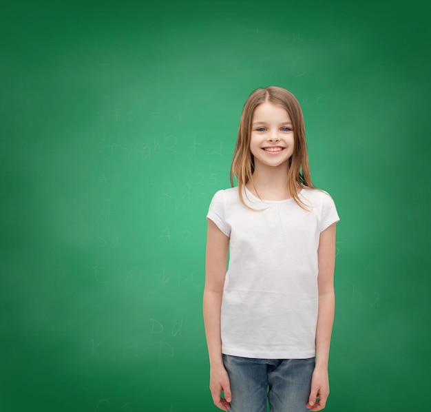 концепция дизайна рекламы и футболки - улыбающаяся маленькая девочка в белой пустой футболке на белом фоне