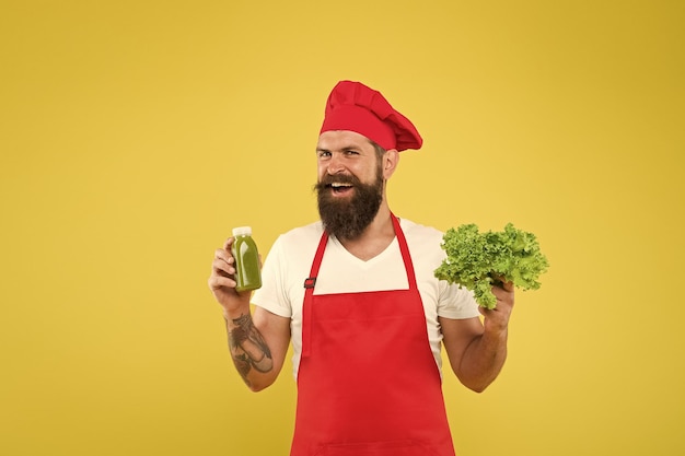 Advertising your product healthy eating and diet concept cook hold fresh salad and smoothie in bottle organic eco vegan products bearded man chef in apron and hat hipster decide what to choose