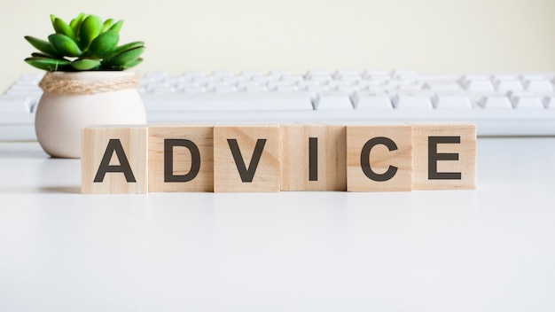 Advice word made with wooden blocks. front view concepts, green plant in a flower vase and white keyboard on background