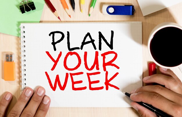 Advies voor het plannen van uw week in rode tekst op een gele kleverige briefje die als herinnering op de bladzijde van een kalender wordt geplaatst