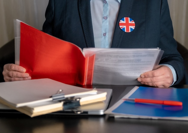 Advocaat of kantoormedewerker of ambtenaar in de buurt van zijn werkplek met de vlag van Groot-Brittannië op een jaspictogram