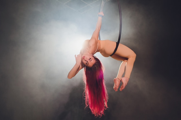 Aerial acrobat in the ring. A young girl performs the acrobatic elements in the air ring.