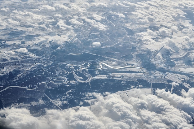 Vista aerea del cloudscape sopra le nuvole dall'alto ai fiumi innevati, strade, città e campi, aria invernale