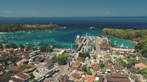 緑のジャングルの森、赤い屋根の村、オーシャンベイの港の港と桟橋の旅の上空のドローン飛行