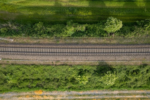 Aerial drone shot of a railroad in between rural fields and vegetation