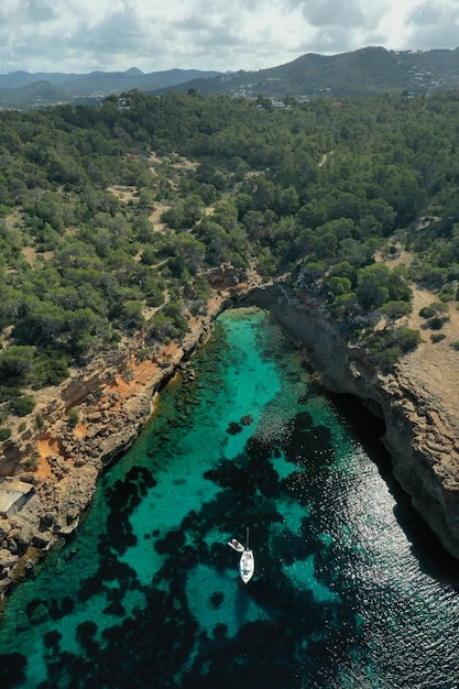 Foto foto aerea dall'alto del drone di una barca ancorata in un'isola esotica ricoperta di pini