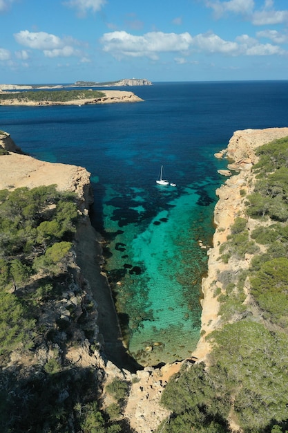 Foto foto aerea dall'alto del drone di una barca ancorata in un'isola esotica ricoperta di pini