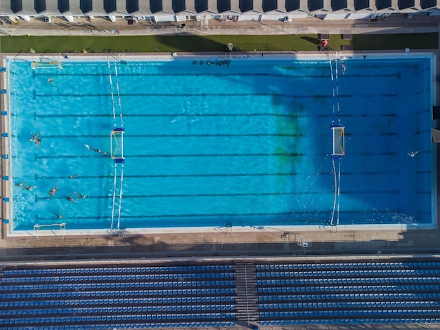 Aerial drone top view shot of people competing in water polo in turquoise water pool