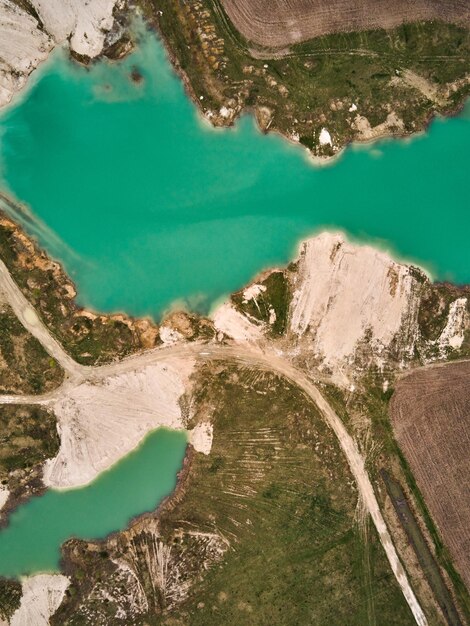 Aerial drone view Amazing industrial landscape on Emerald lake in a flooded quarry opencast mine Oval lake in industrial crater acid mine drainage Open pit mine with lake