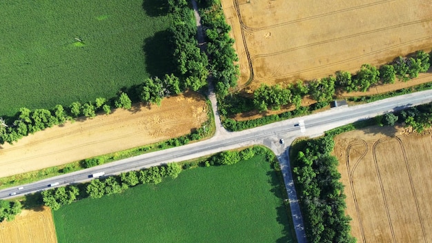 Aerial drone view over asphalt road intersection between agricultural fields