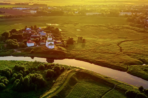 Aerial drone view of the church of elijah the prophet at the\
kamenka river, russia. summer sunny day sunset.