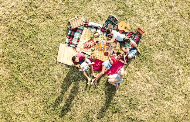 Aerial drone view of happy families having fun with kids at picnic barbecue party