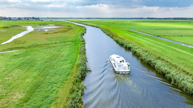 Aerial drone view of houseboat in canal and country landscape of Holland from above, family travel by barge boat and vacation in Netherlands