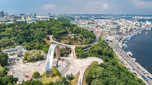 Aerial drone view of new pedestrian cycling park bridge construction, Dnieper river, hills, parks and Kyiv cityscape from above, city of Kiev skyline, Ukraine