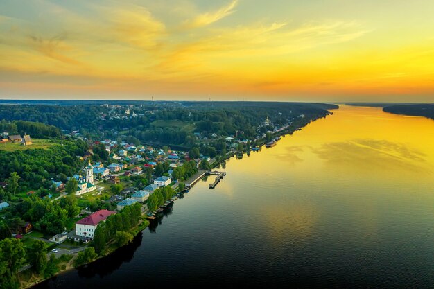 写真 黄色の夕日とヴォルガ川の古代ロシアの町plesの空中ドローンビュー。