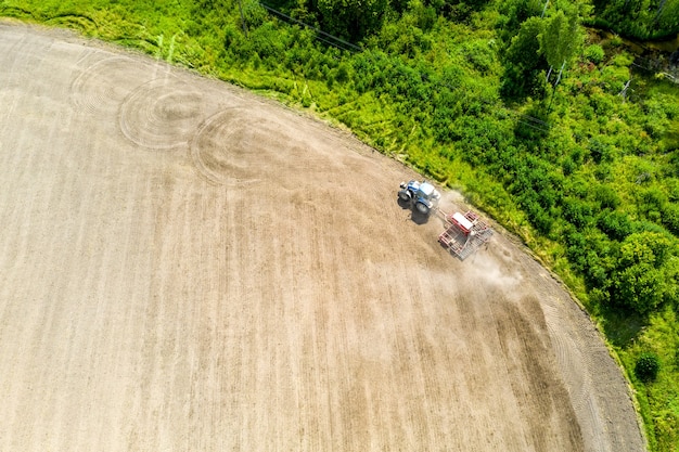 Aerial drone view with beautiful autumn landscape of working tractor on the harvest field. Agriculture concept.