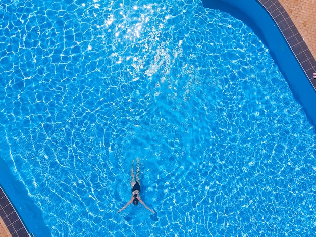 Foto vista aerea del drone della donna che nuota in piscina in hotel
