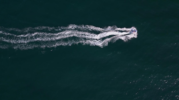 Aerial dynamic view of the water scooter or personal watercraft or ski jet racing through the sea waves