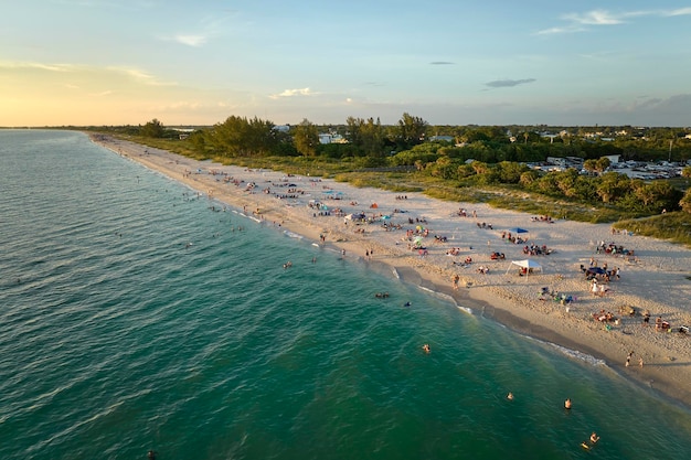 Воздушный вечерний морской пейзаж с песчаным пляжем Нокомис в округе Сарасота, США. Многие туристы наслаждаются летними каникулами, купаясь в теплой воде Мексиканского залива и загорая на горячем солнце Флориды.