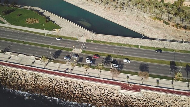 高速道路の車を追って空飛ぶショット岩石の海岸線の空から見た景色