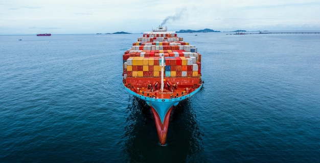 Aerial in front of cargo ship carrying container and running for export goods from cargo yard port to custom ocean concept freight shipping by ship