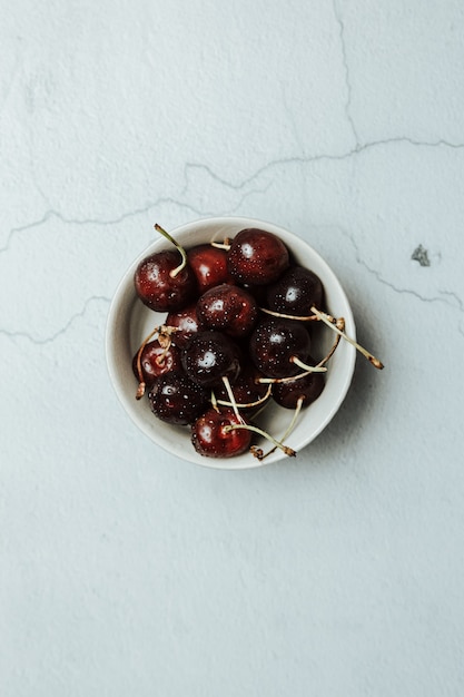 Aerial image of a dish filled with cherries over a white marble table, fresh food, wellness, healthy food