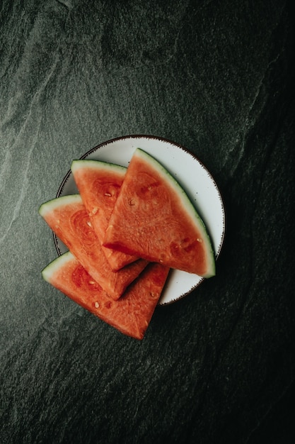 Aerial image of a dish filled with watermelon over a black marble table, fresh food, wellness, healthy food