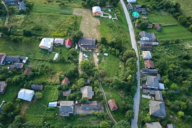 Aerial landscape view of green cultivated agricultural fields with growing crops and distant village houses