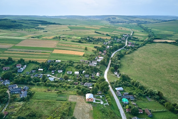 Aerial landscape view of green cultivated agricultural fields with growing crops and distant village houses