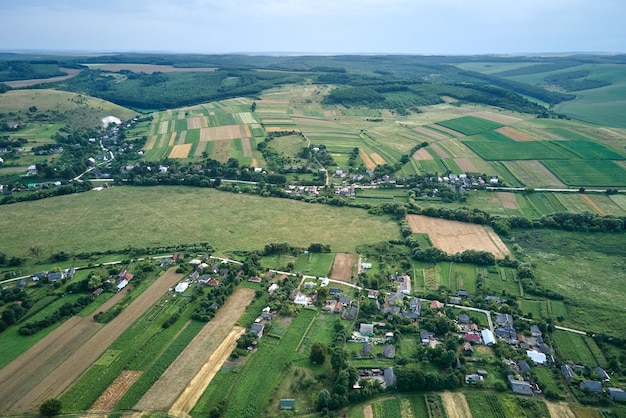 写真 明るい夏の日に作物が育つ村の家と遠くの緑の耕作された農地の空中風景ビュー