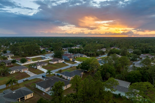 Aerial landscape view of suburban private houses between green palm trees in Florida quiet rural area at sunset