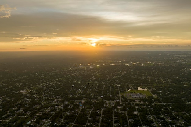 Aerial landscape view of suburban private houses between green palm trees in Florida quiet rural area at sunset