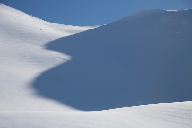 Aerial landscape of white snow forming a graphic texture play of light and shadows