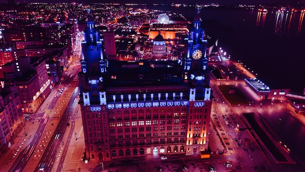 Aerial night view of an illuminated urban cityscape with skyscrapers and a waterfront in Liverpool UK