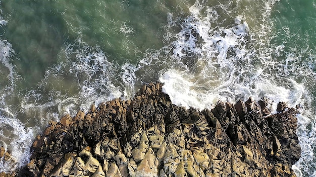 写真 険しい岩に対して美しい砕ける海の波の空中俯瞰図