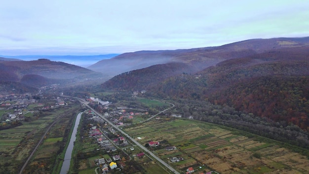 秋の山の丘の間に小さな家が覆われた村の農村地域の空中パノラマビューy