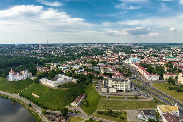 Aerial panoramic view from great height on red roofs of old big city with skyscrapers and white fluffy clouds