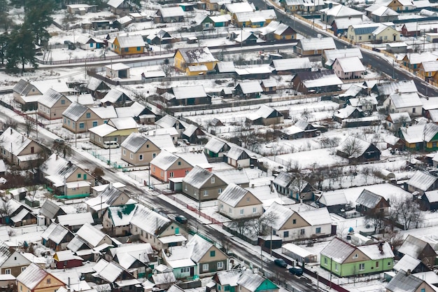 Aerial panoramic winter view of village with houses barns and gravel road with snow