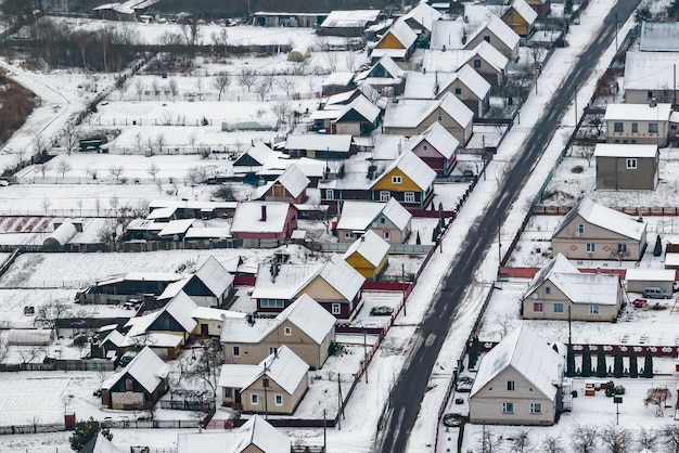 Aerial panoramic winter view of village with houses barns and\
gravel road with snow