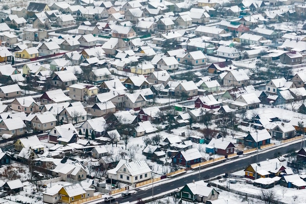 Aerial panoramic winter view of village with houses barns and\
gravel road with snow