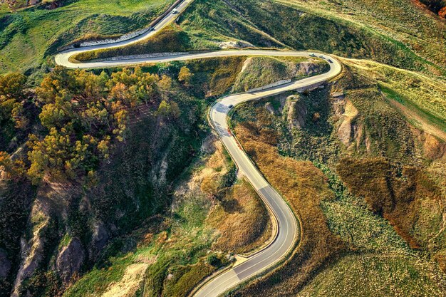 Aerial photo of a curved mountain road under the mountain peak