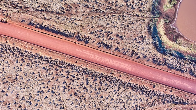 砂漠の平原の赤い未舗装の道路の航空写真