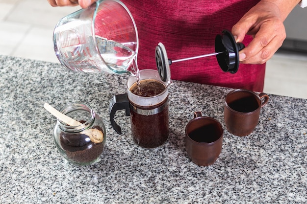 얼굴이 보이지 않는 바리스타가 부엌에서 커피 두 잔을 준비하는 모습을 항공사진으로 카운터 위에 놓고 끓는 물을 올려놓고 선택적 초점