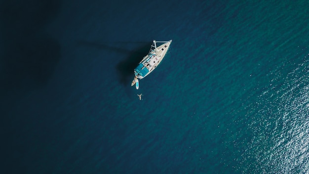 Aerial shot of beautiful blue lagoon at hot summer day with sailing boat. Top view.