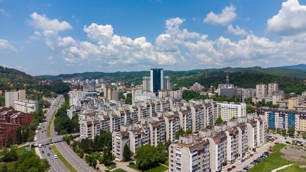 Aerial shot of a city buildings surrounded by mountain on a cloudy sky background