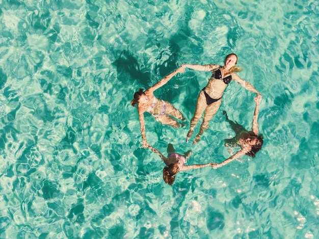 Aerial shot of a four beautiful female friends having fun in the clear sea.