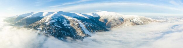 Aerial shot of majestic sunrise in the mountains Valley between the mountains is covered with fog and is illuminated by the warm rays of the rising sun Mountains covered with forest natural