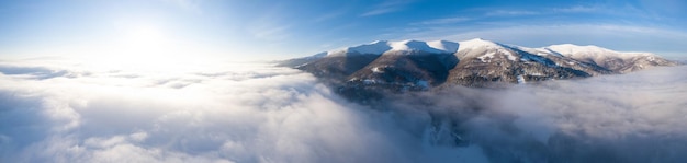 Aerial shot of majestic sunrise in the mountains Valley between the mountains is covered with fog and is illuminated by the warm rays of the rising sun Mountains covered with forest natural