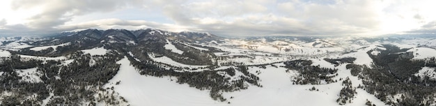 Aerial shot of majestic sunrise in the mountains Valley between the mountains is covered with fog and is illuminated by the warm rays of the rising sun Mountains covered with forest natural